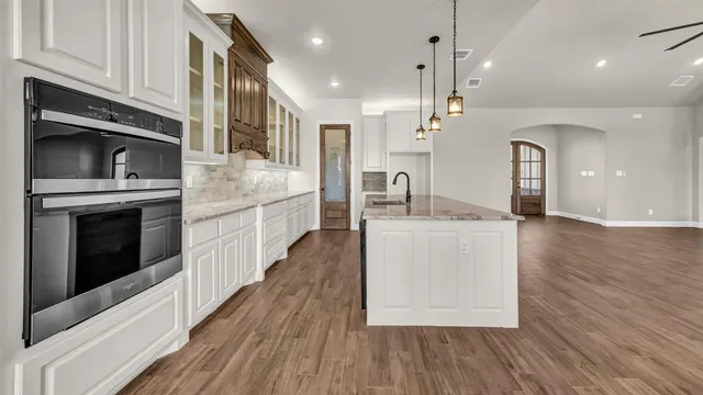 a kitchen with kitchen island granite countertop a stove top oven a sink and wooden floors
