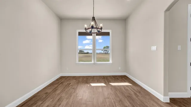 a very nice looking room with wooden floor a ceiling fan and windows