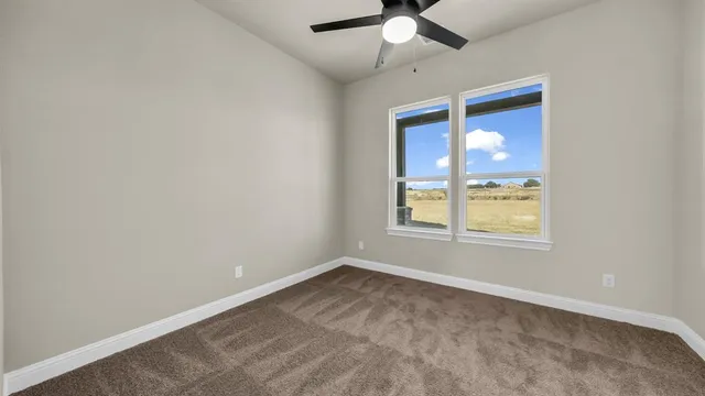 an empty room with a window and a chandelier fan