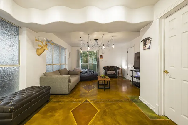 a living room with furniture a chandelier and a dining table