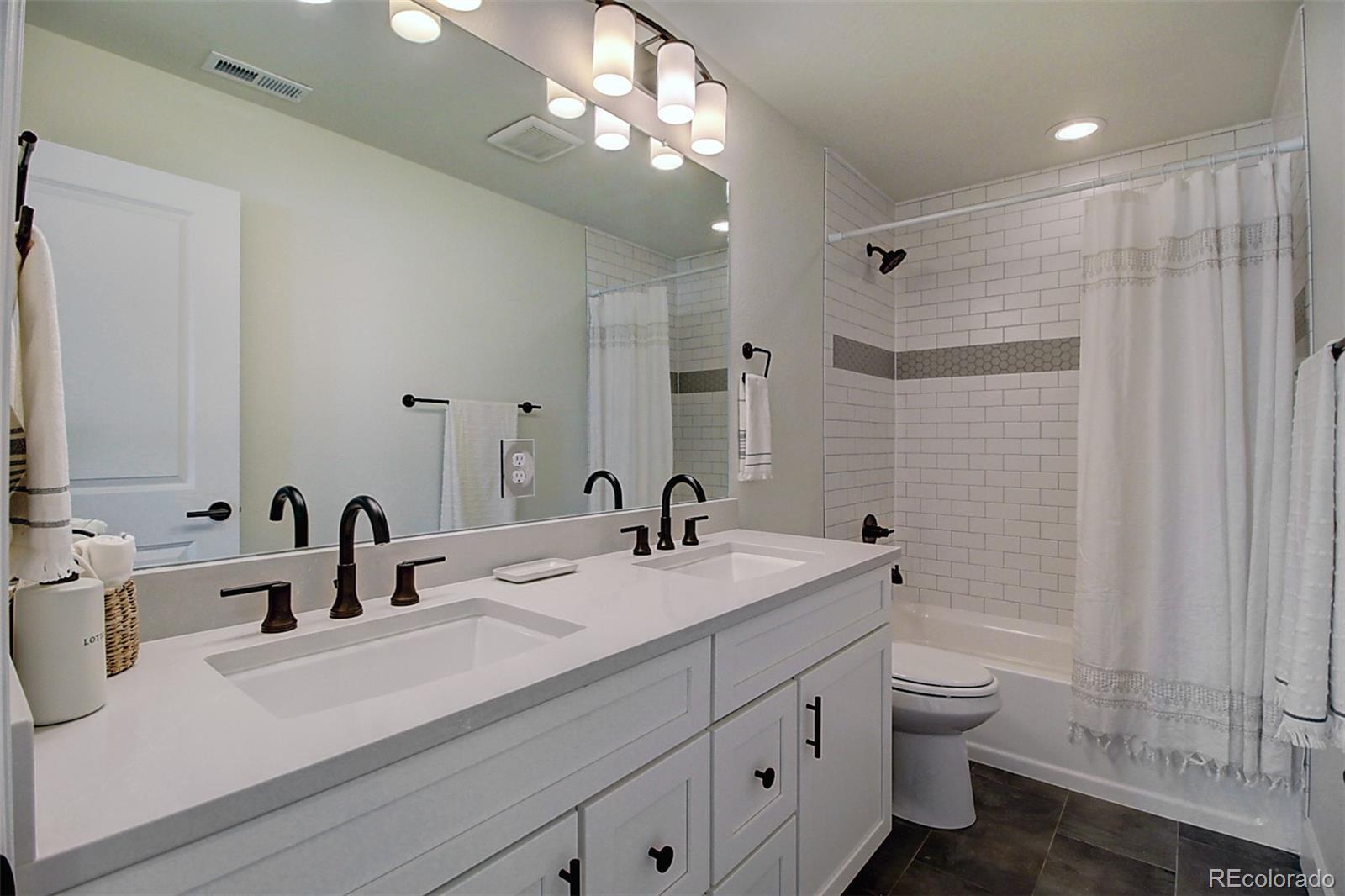 1013 Gabriella Lane Berthoud, CO 80513 - Photo 23 of 39 a bathroom with double vanity sink a toilet a shower and a mirror