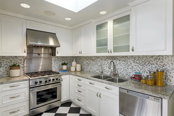 a kitchen with stainless steel appliances granite countertop a sink stove and cabinets