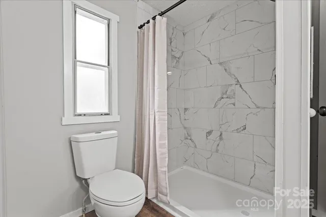 a white toilet sitting next to a shower