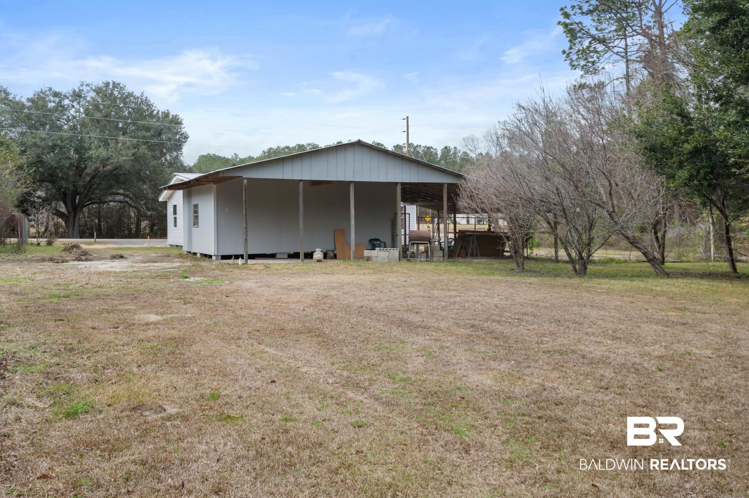 35780 Spring Road North Stapleton, AL 36578 - Photo 36 of 41 Rear view of property featuring a wooden deck, a yard, and an outbuilding