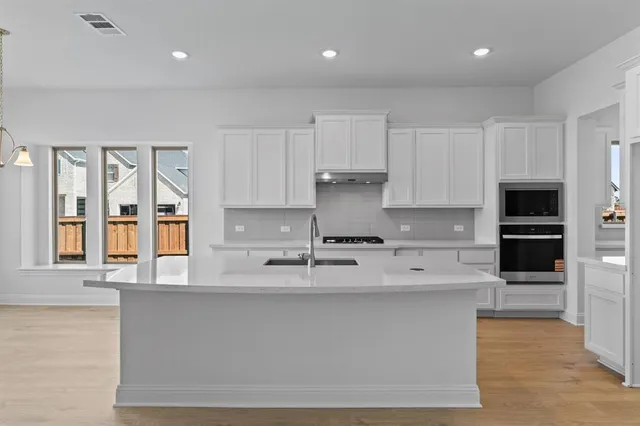 a large kitchen with stainless steel appliances granite countertop a lot of counter space and a sink