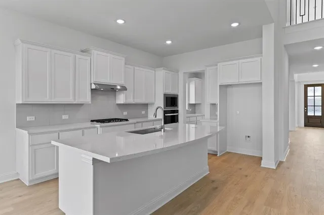 a large white kitchen with granite countertop a large window