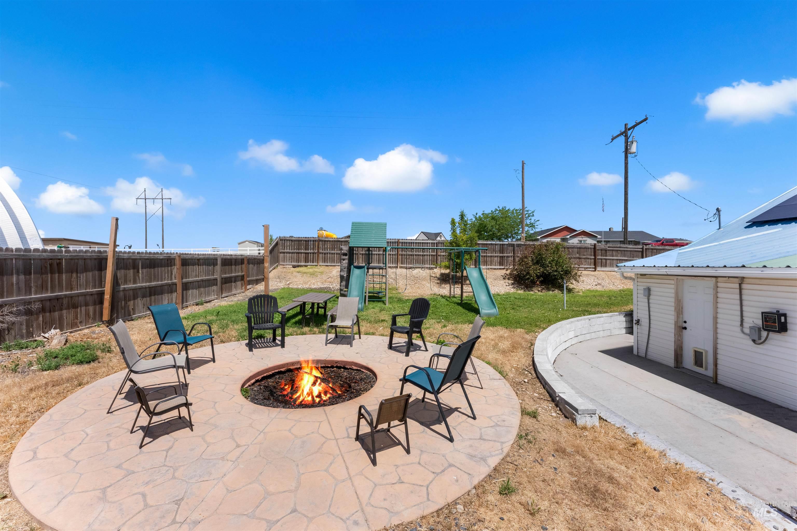 17441 Upper Pleasant Ridge Road Caldwell, ID 83607 - Photo 34 of 40 Backyard featuring a stamped concrete fire pit area, a green space, and a wood fence boundary