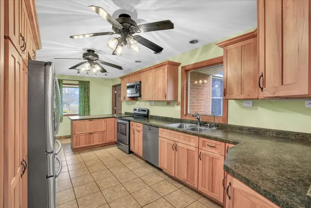 a kitchen with stainless steel appliances granite countertop a stove top oven a sink dishwasher a dining table and chairs with wooden floor