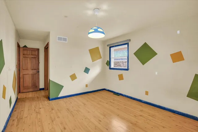 an empty room with ceiling fan and windows