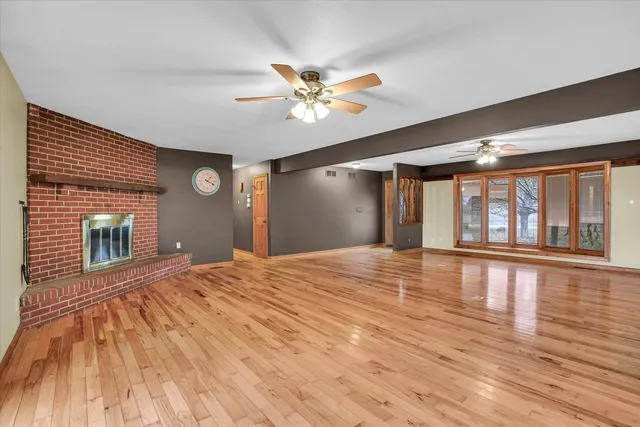 a view of an empty room with window and wooden floor