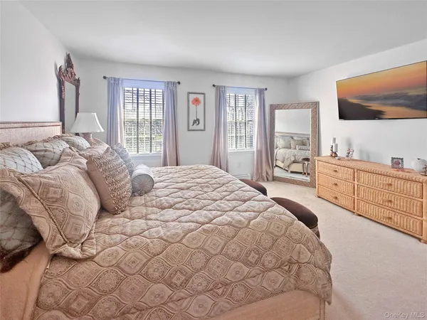a large white bed sitting in a bedroom next to a window