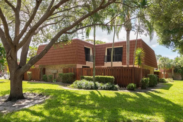 a view of a yard in front of a house with plants and large tree