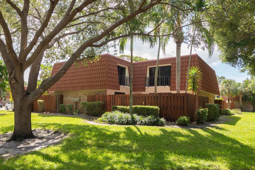 3118 Spanish Wells Drive, Unit 15C Delray Beach, FL 33445 - Photo 2 of 40 a view of a yard in front of a house with plants and large tree