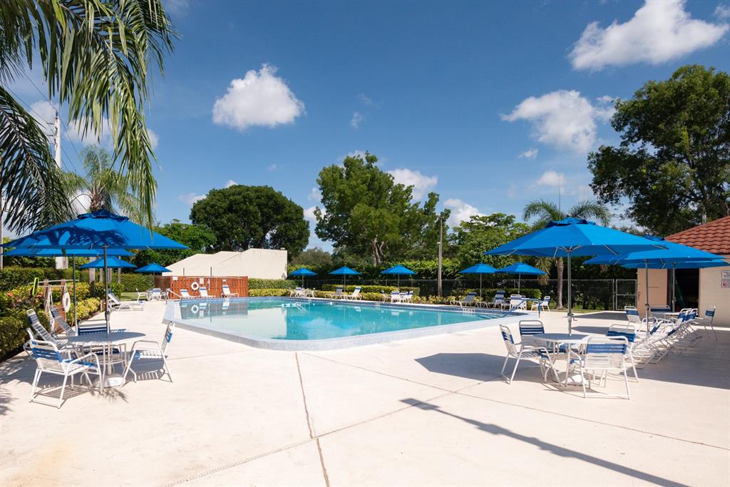 3118 Spanish Wells Drive, Unit 15C Delray Beach, FL 33445 - Photo 28 of 40 a patio with a table and chairs under an umbrella