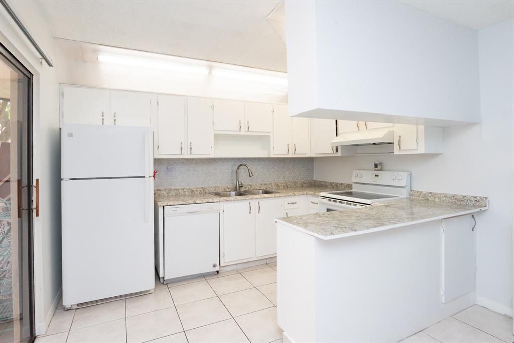 3118 Spanish Wells Drive, Unit 15C Delray Beach, FL 33445 - Photo 9 of 40 a kitchen with a refrigerator sink stove and cabinets
