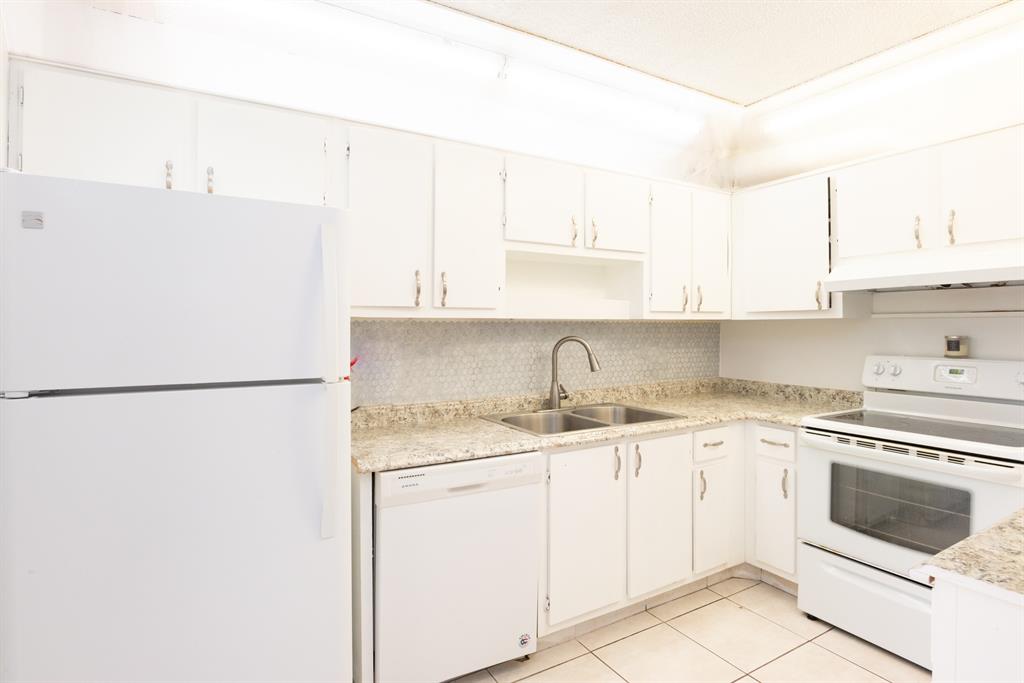 3118 Spanish Wells Drive, Unit 15C Delray Beach, FL 33445 - Photo 10 of 40 a kitchen with a white cabinets and white appliances