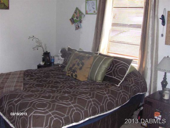 5494 Riverside Drive Port Orange, FL 32127 - Photo 8 of 13 a bed sitting in a bedroom next to a window