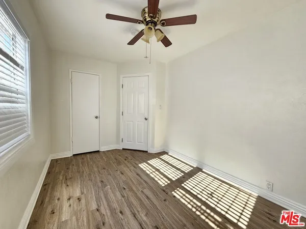 a view of a room with wooden floor ceiling fan and window