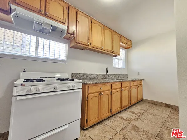 a kitchen with granite countertop a sink stove and cabinets