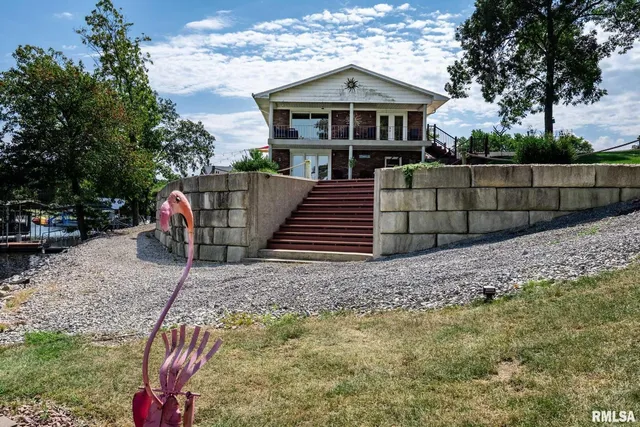 a view of a house with a yard potted plants and large tree