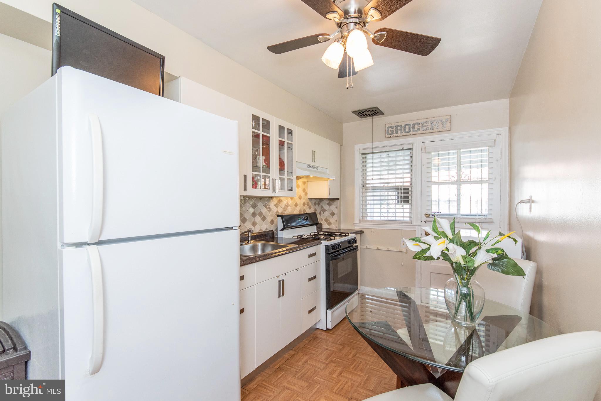 1520 Winford Road Baltimore, MD 21239 - Photo 8 of 30 a white kitchen with stainless steel appliances granite countertop a refrigerator a sink a stove a dining table and chairs