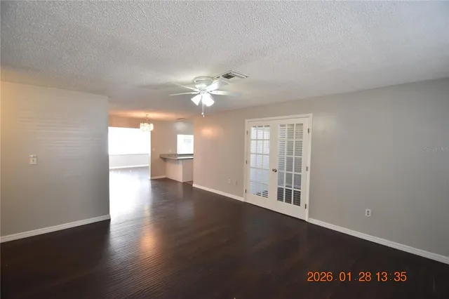 an empty room with wooden floor fan and window