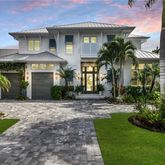 a front view of a house with a yard and palm trees