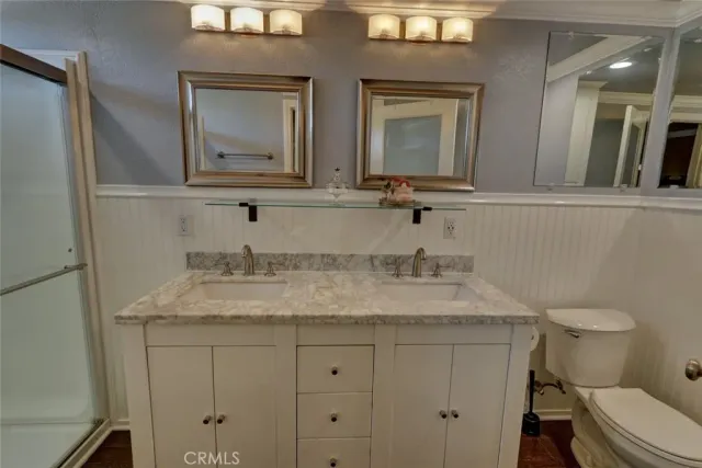 a bathroom with a granite countertop sink vanity mirror and toilet