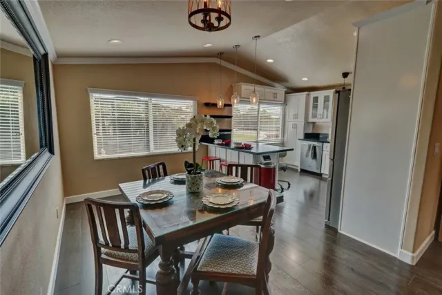 a dining room with stainless steel appliances furniture a window and kitchen view