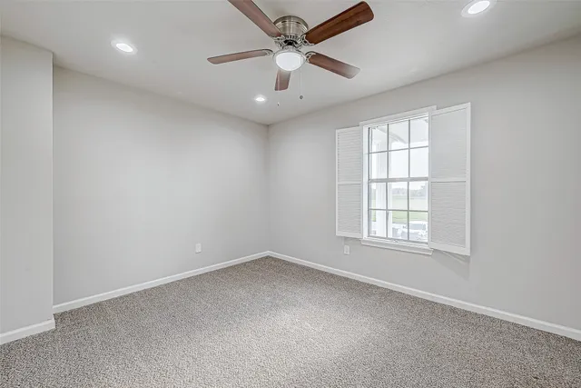 an empty room with windows and fan
