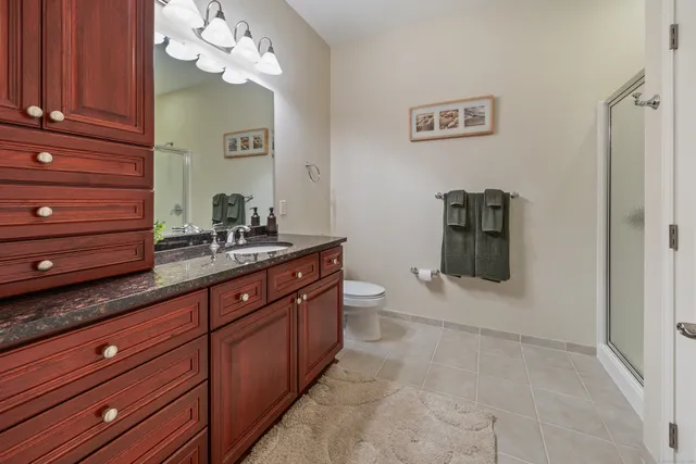 a spacious bathroom with a granite countertop sink a mirror and shower