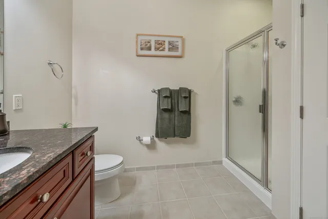 a bathroom with a granite countertop sink a toilet and shower