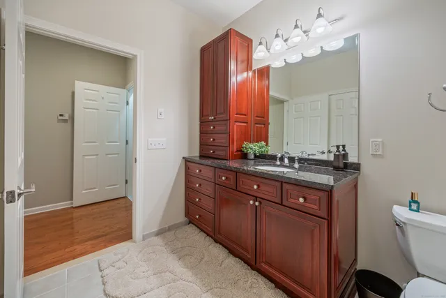 a spacious bathroom with a granite countertop sink a toilet and a mirror