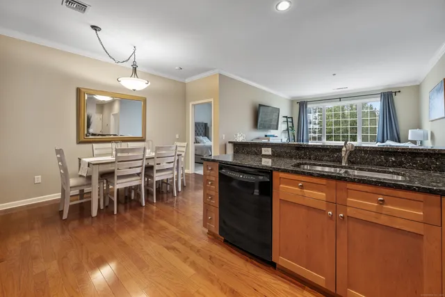 a kitchen with stainless steel appliances granite countertop a stove a sink a dining table and chairs with wooden floor