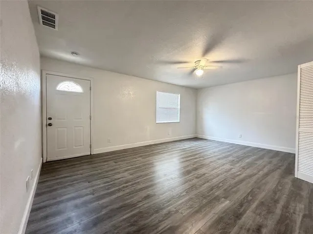a view of an empty room with window and wooden floor