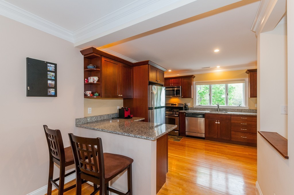 38 Lafayette Street, Unit 38 Arlington, MA 02474 - Photo 3 of 13 a kitchen with stainless steel appliances granite countertop a stove a sink a refrigerator white cabinets with dining table and chairs