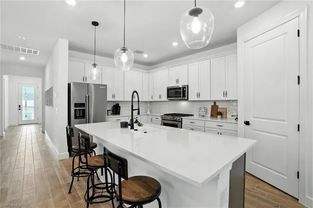 a kitchen with stainless steel appliances a table chairs and a refrigerator