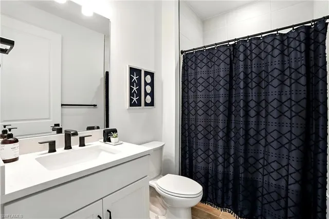 a bathroom with a sink a toilet and shower curtain
