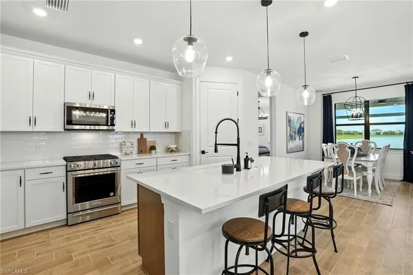 a kitchen with stainless steel appliances a table chairs and white cabinets