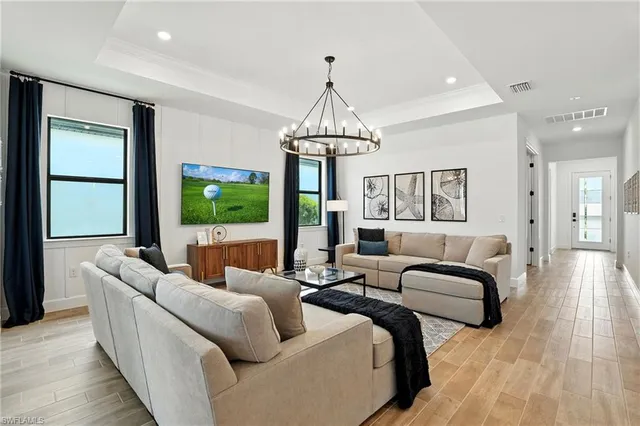 a living room with furniture a large window and a chandelier