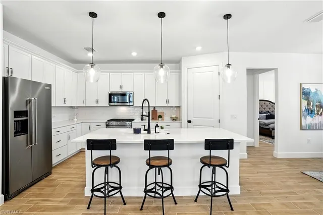 a kitchen with stainless steel appliances kitchen island granite countertop a dining table chairs and white cabinets