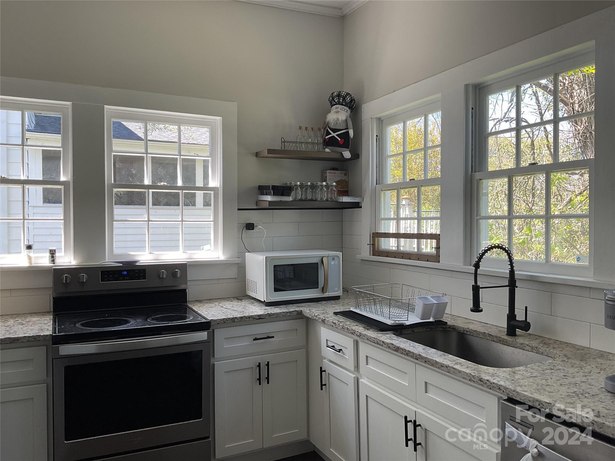 a kitchen with granite countertop a stove a sink and wooden cabinets