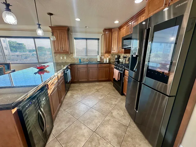 a kitchen with granite countertop a refrigerator stove top oven and sink