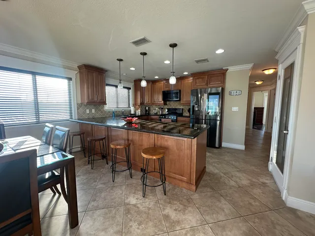 a kitchen with stainless steel appliances a refrigerator a sink a stove a washer dryer and wooden cabinets