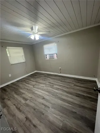 a view of an empty room with window and wooden floor