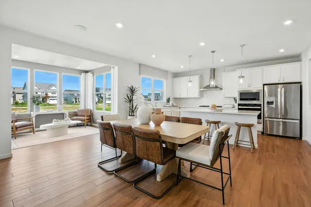 a kitchen with stainless steel appliances wooden floor dining table and chairs