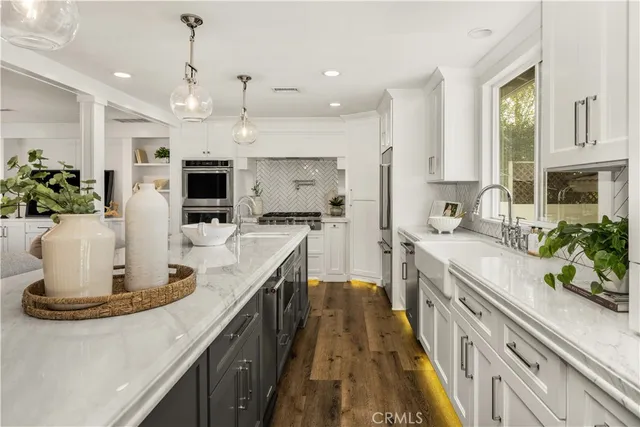 a large kitchen with kitchen island a large counter top stainless steel appliances and cabinets