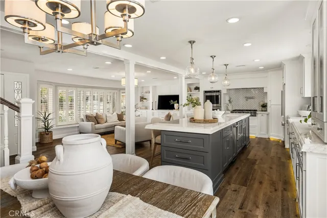 a large white kitchen with a stove a sink dishwasher and a dining table with wooden floor