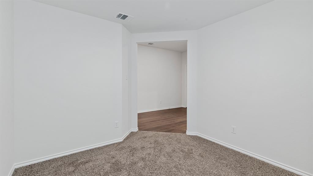 4028 Ripplewood Drive Lindale, TX 75771 - Photo 28 of 31 Carpeted room with white walls, white trim, and a doorway opening to a room with wood-finish flooring