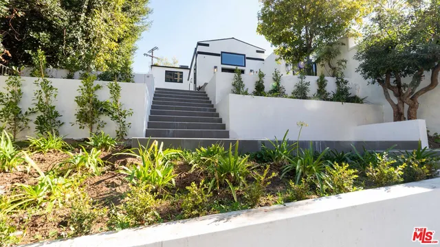 a view of a house with a yard and potted plants